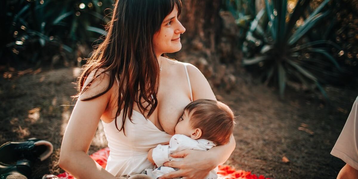 Moeder geeft haar baby borstvoeding buiten op een deken