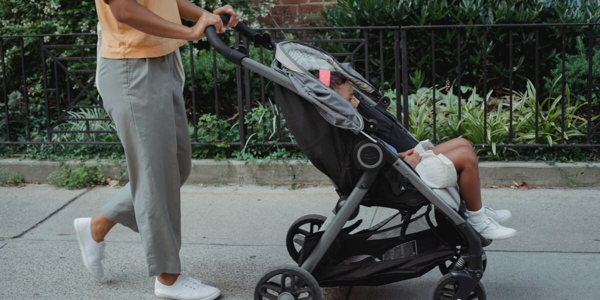 Lichte buggy opgevouwen gedragen met een kind op de arm in de stad