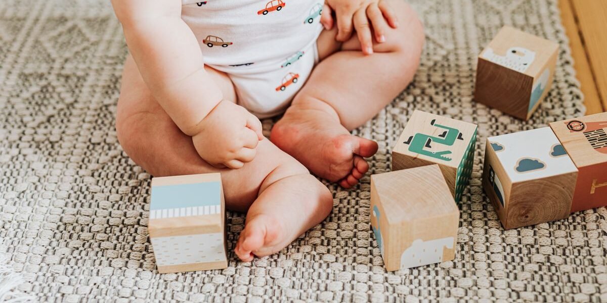 Baby van 6 tot 12 maanden speelt met houten blokken op een kleed