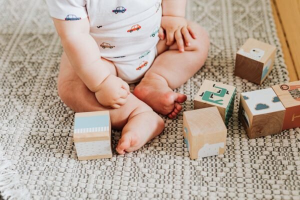 Baby van 6 tot 12 maanden speelt met houten blokken op een kleed