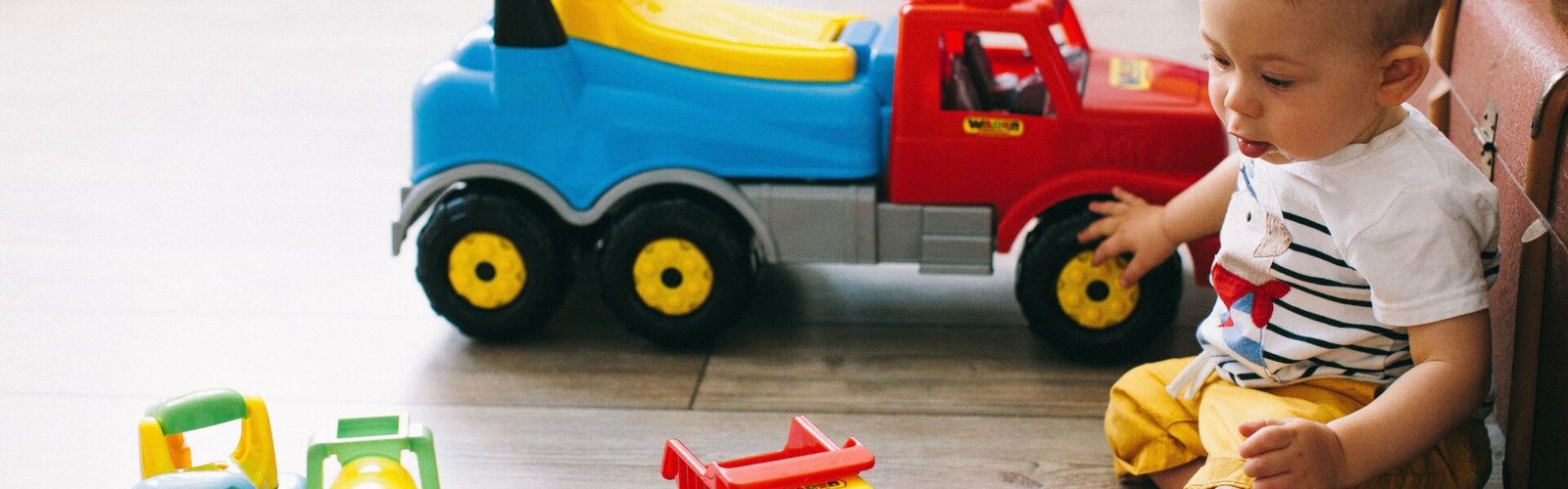 Babyjongen speelt met zijn cadeau, een kleurrijke speelgoedauto