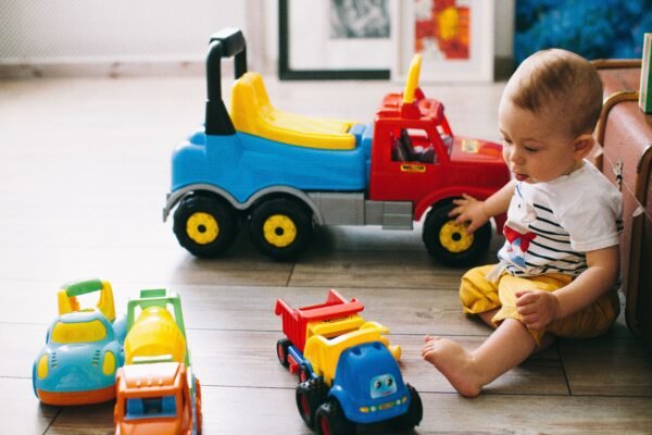 Babyjongen speelt met zijn cadeau, een kleurrijke speelgoedauto