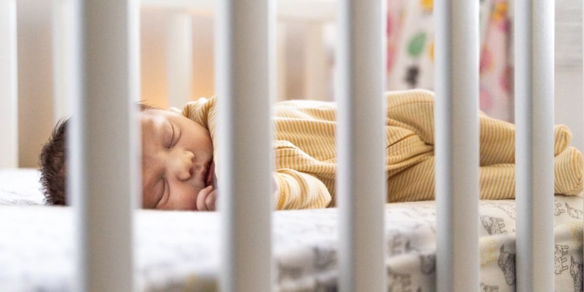 Baby slaapt rustig in een wieg met de juiste slaapzak dikte
