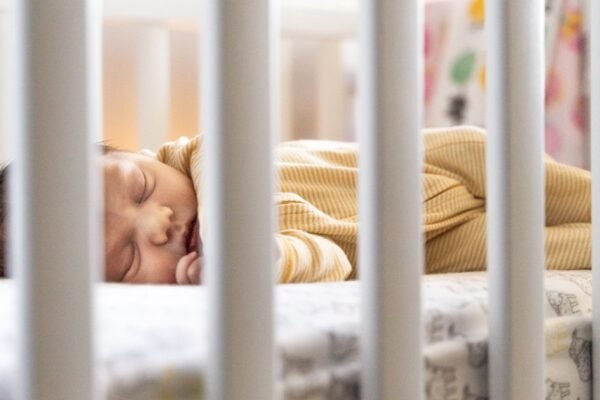 Baby slaapt rustig in een wieg met de juiste slaapzak dikte