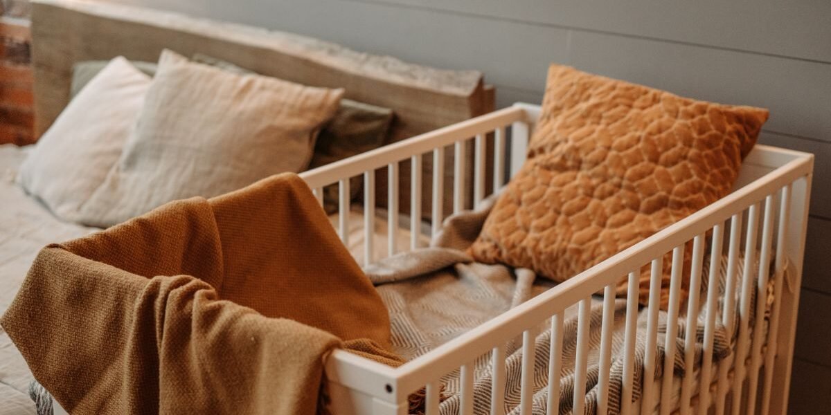 co-sleeper naast een hoog bed met warme dekentjes in de slaapkamer