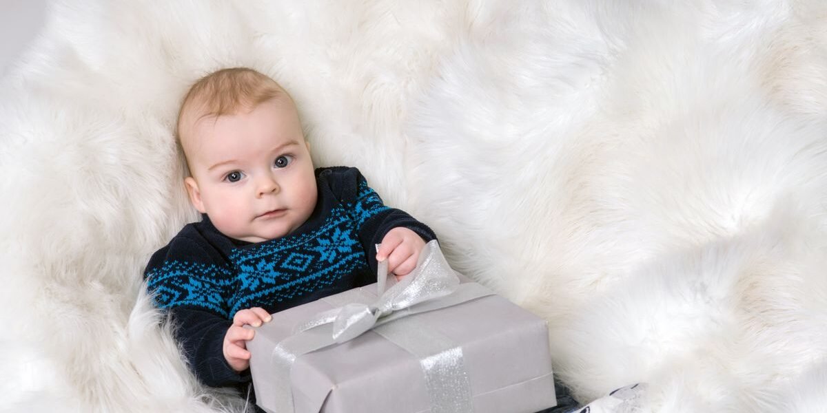 Baby houdt een ingepakt babycadeau vast op een witte vacht