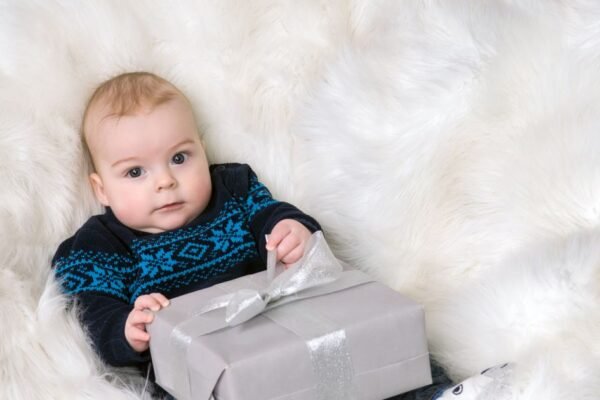 Baby houdt een ingepakt babycadeau vast op een witte vacht