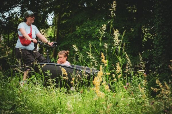 Ouder fietst met kind buiten, thema fietskar voor 2 kinderen