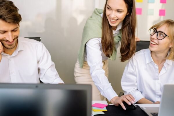 Collega's bekijken samen een geboortelijst op een laptop op kantoor