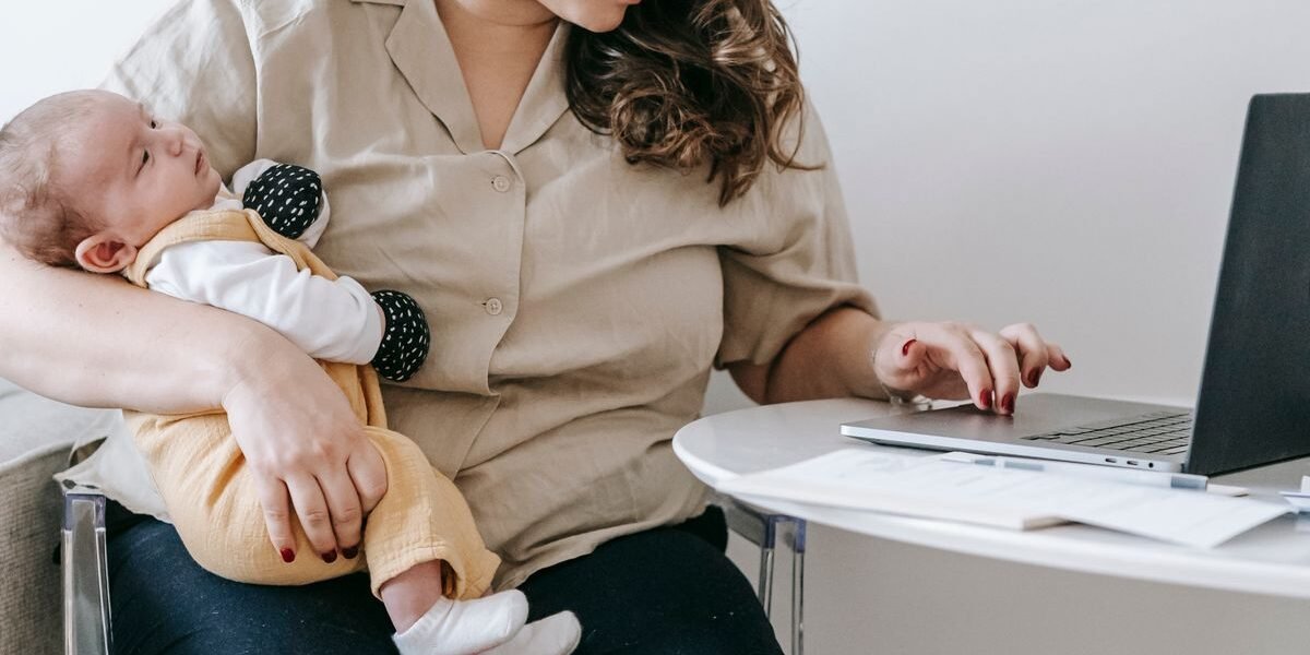 Moeder met baby bekijkt haar geboortelijst online op een laptop