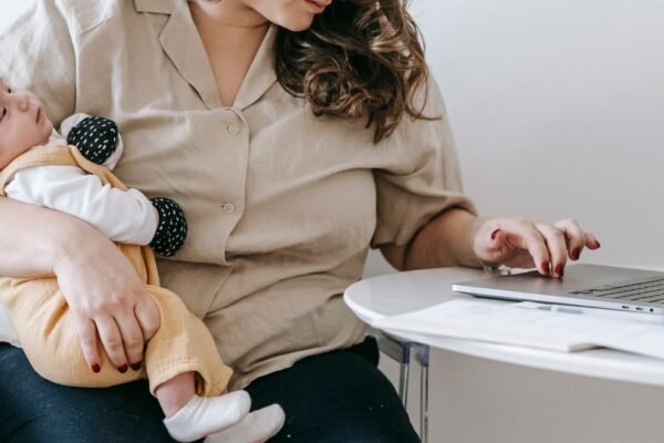 Moeder met baby bekijkt haar geboortelijst online op een laptop