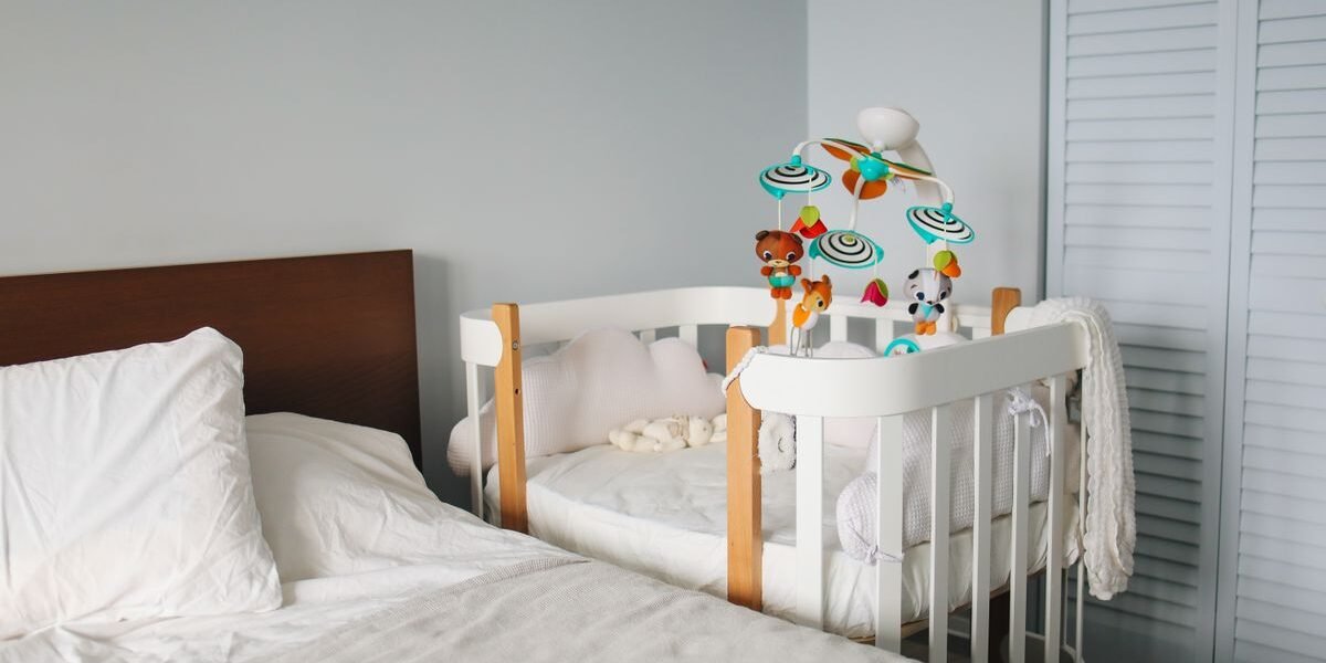 Compact wit babybed in de hoek van een kleine slaapkamer