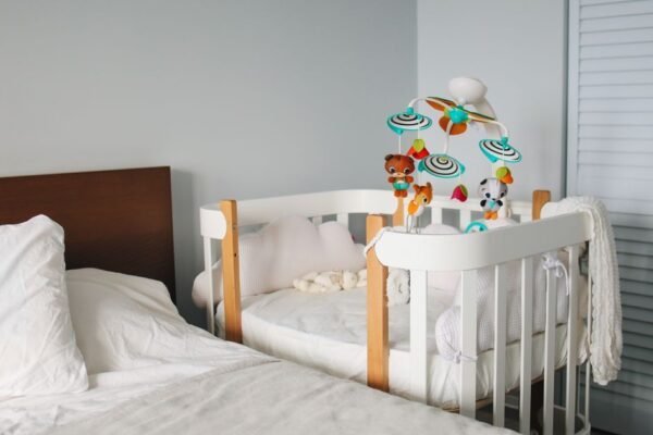 Compact wit babybed in de hoek van een kleine slaapkamer