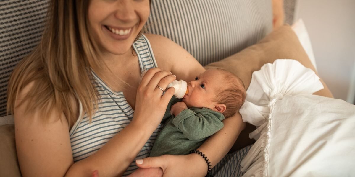 Moeder geeft haar pasgeboren baby gekolfde moedermelk met een flesje