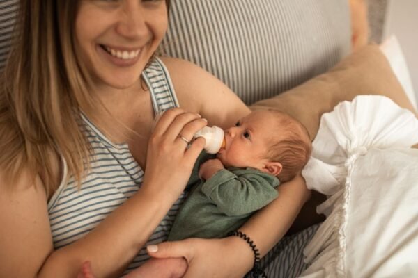 Moeder geeft haar pasgeboren baby gekolfde moedermelk met een flesje