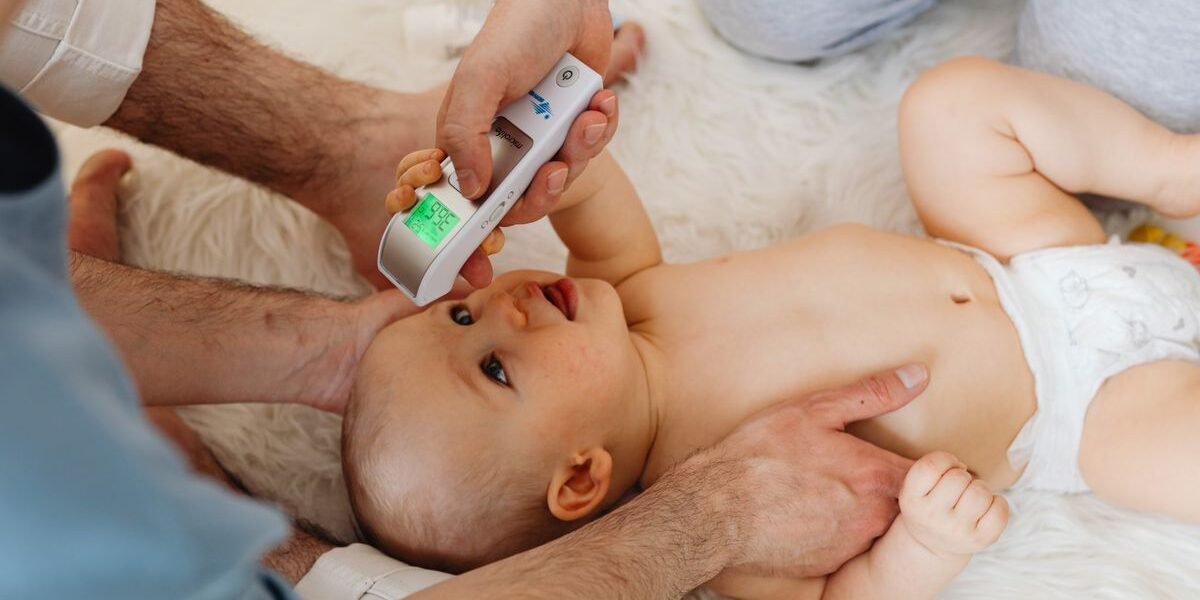 Ouder meet de temperatuur van een baby met een digitale koortsthermometer
