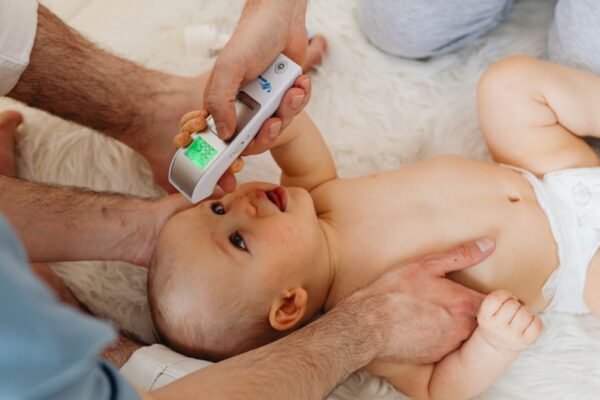 Ouder meet de temperatuur van een baby met een digitale koortsthermometer