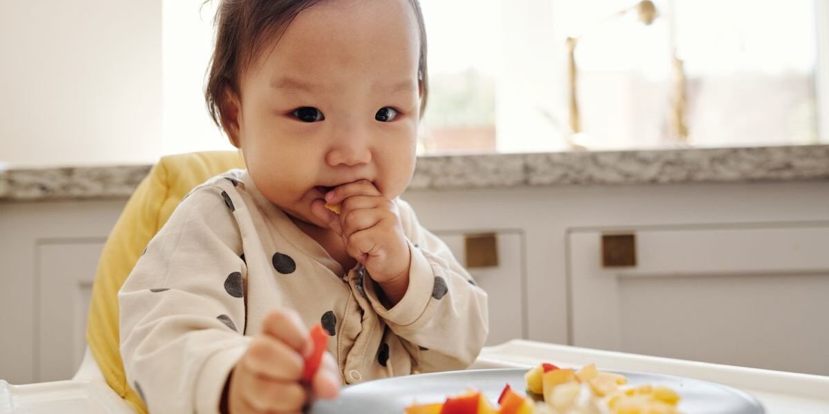 baby eet vast voedsel in kinderstoel