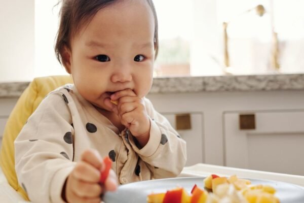 baby eet vast voedsel in kinderstoel