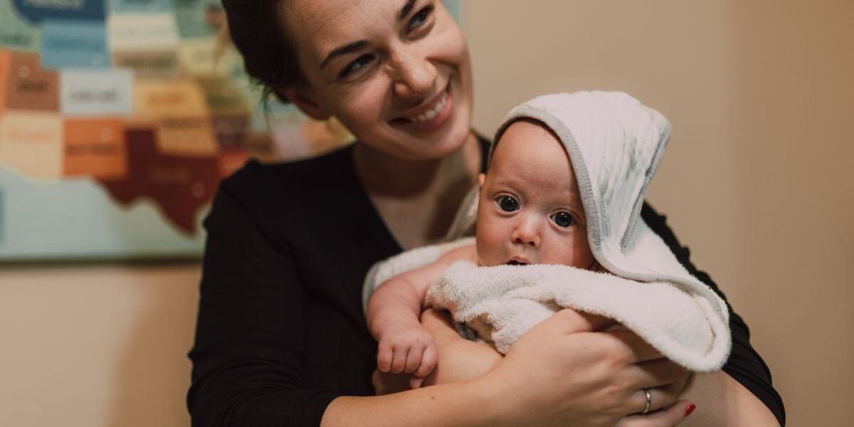 Moeder houdt pasgeboren baby in een warme handdoek thuis na een thuisbevalling
