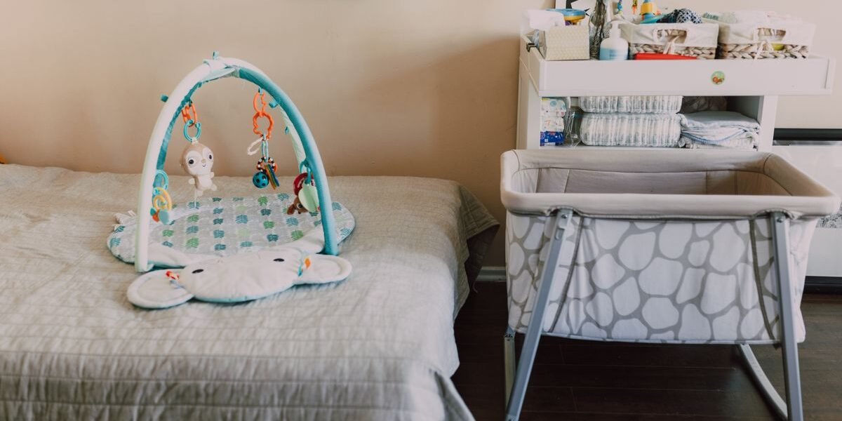 Mobiele verrijdbare wieg naast het ouderlijk bed in een lichte kamer