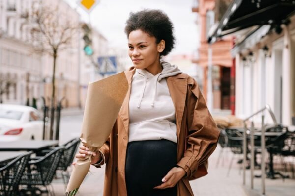 Zwangere vrouw met bloemen tijdens een zwangerschapsfotoshoot buiten