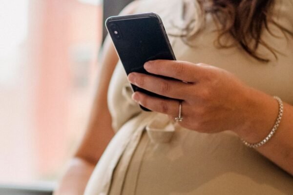 Zwangere vrouw typt een adresverzoek voor het geboortekaartje op haar telefoon