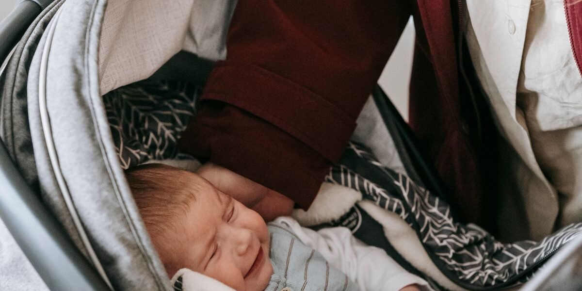 Pasgeboren baby in een achterwaartse i-Size autostoel op de achterbank