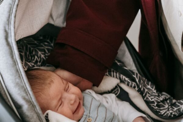 Pasgeboren baby in een achterwaartse i-Size autostoel op de achterbank