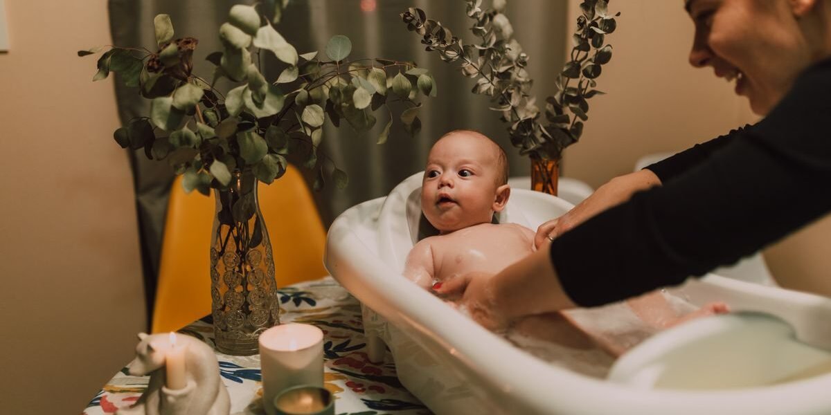 Baby in babybadje op standaard met badthermometer en badcape