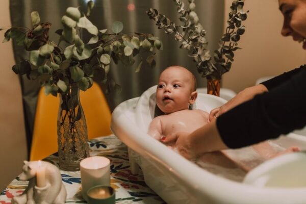 Baby in babybadje op standaard met badthermometer en badcape