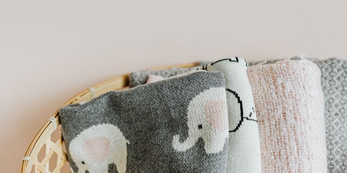 Gebreid baby dekentje opgevouwen op wieg naast geboortelijst