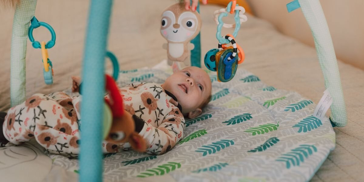 Baby speelgoed 0-3 maanden: baby onder babygym kijkt naar hangers