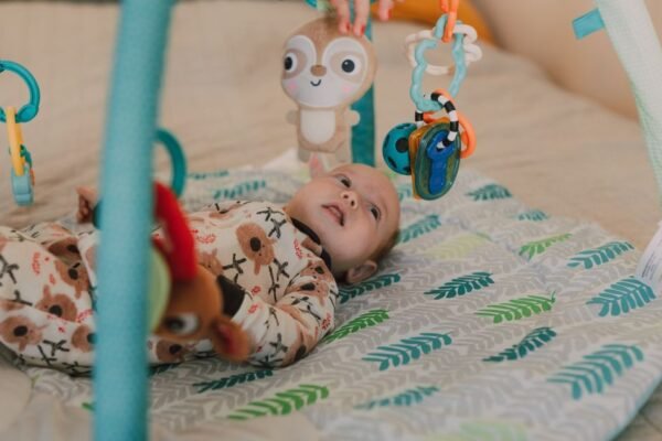 Baby speelgoed 0-3 maanden: baby onder babygym kijkt naar hangers