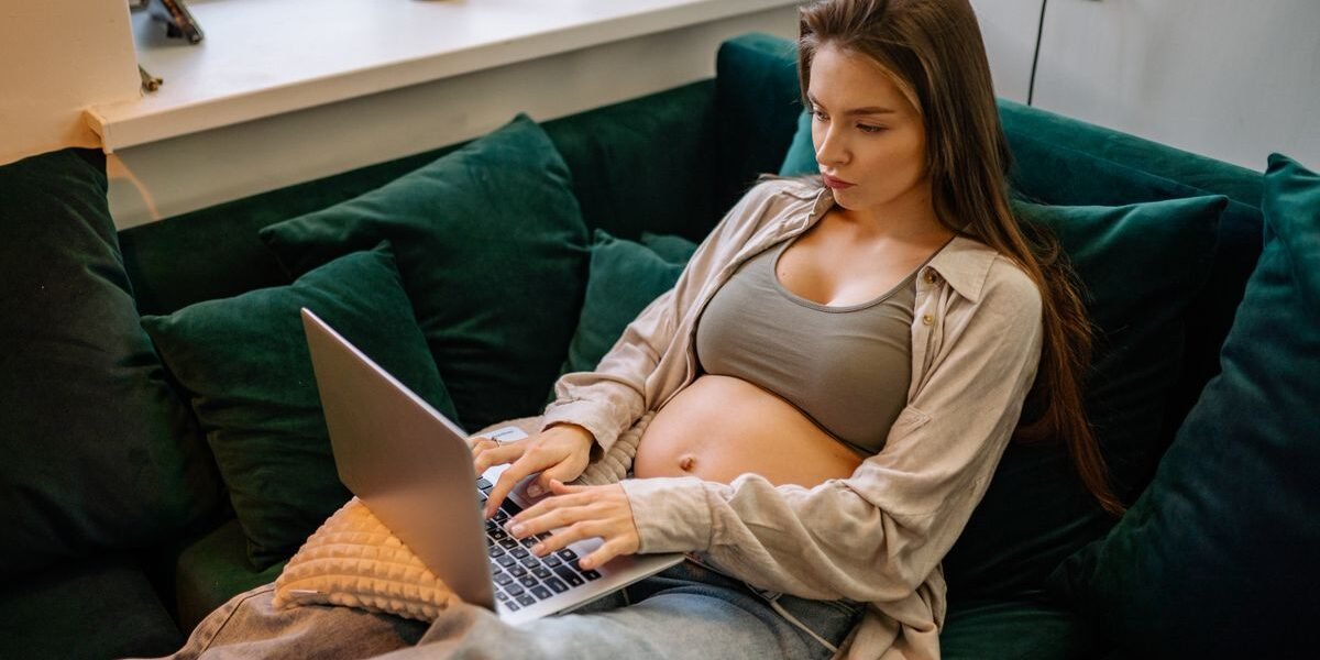 Zwangere vrouw vinkt baby uitzetlijst af op laptop