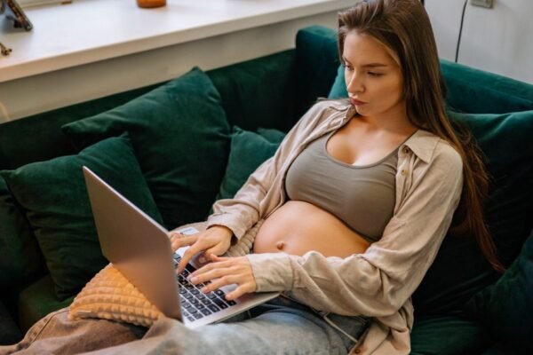 Zwangere vrouw vinkt baby uitzetlijst af op laptop