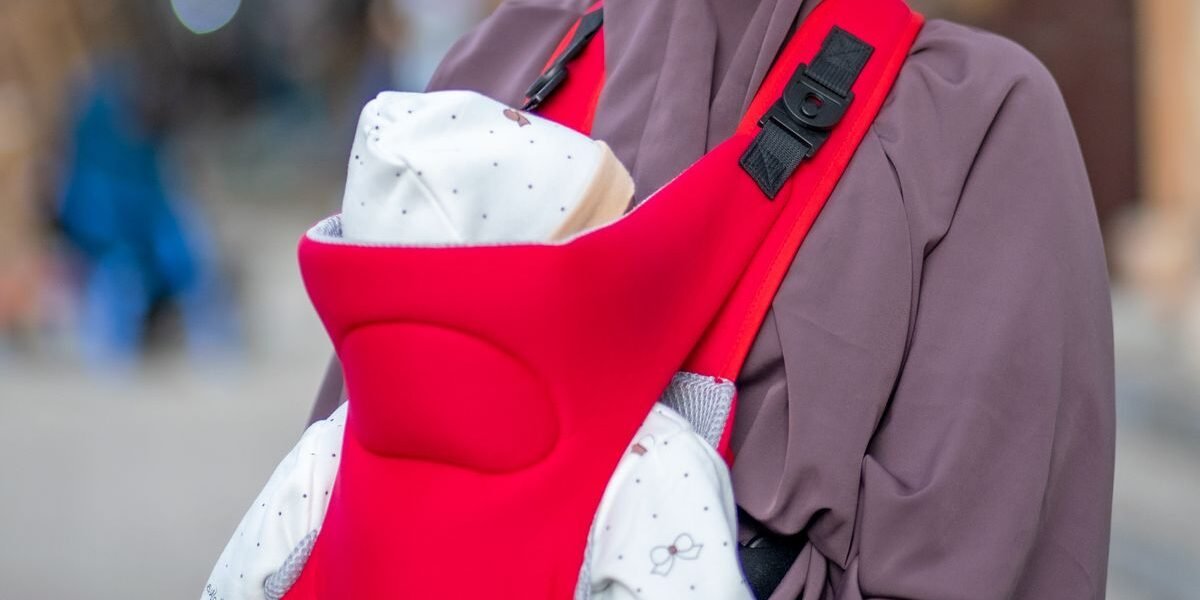 Ouder draagt pasgeboren baby in een ergonomische babydrager