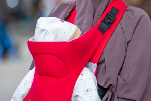 Ouder draagt pasgeboren baby in een ergonomische babydrager