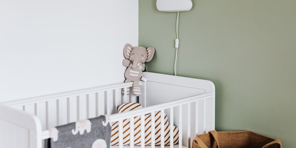 Ingerichte babykamer met ledikant, commode en nachtlampje in zachte kleuren