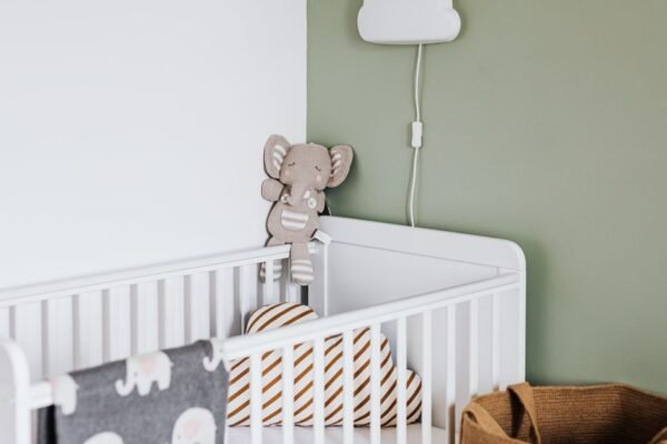 Ingerichte babykamer met ledikant, commode en nachtlampje in zachte kleuren