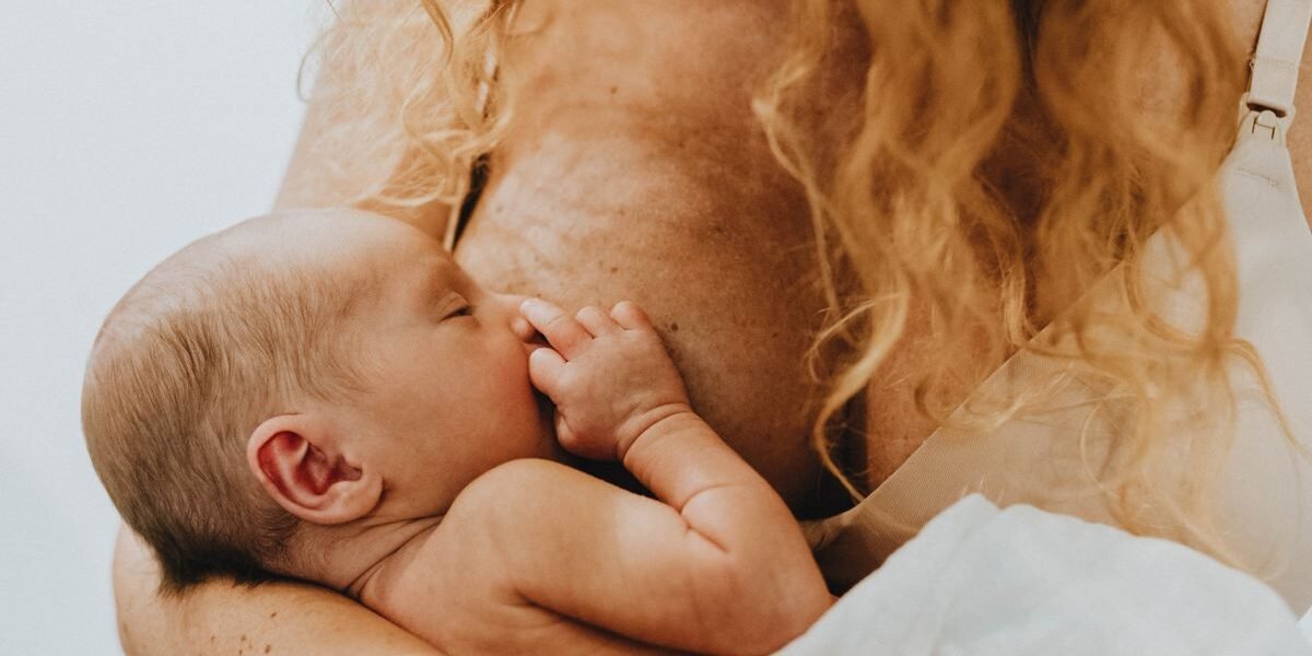 Moeder geeft borstvoeding aan pasgeboren baby in een stoel