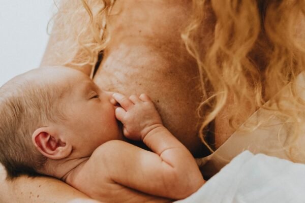 Moeder geeft borstvoeding aan pasgeboren baby in een stoel