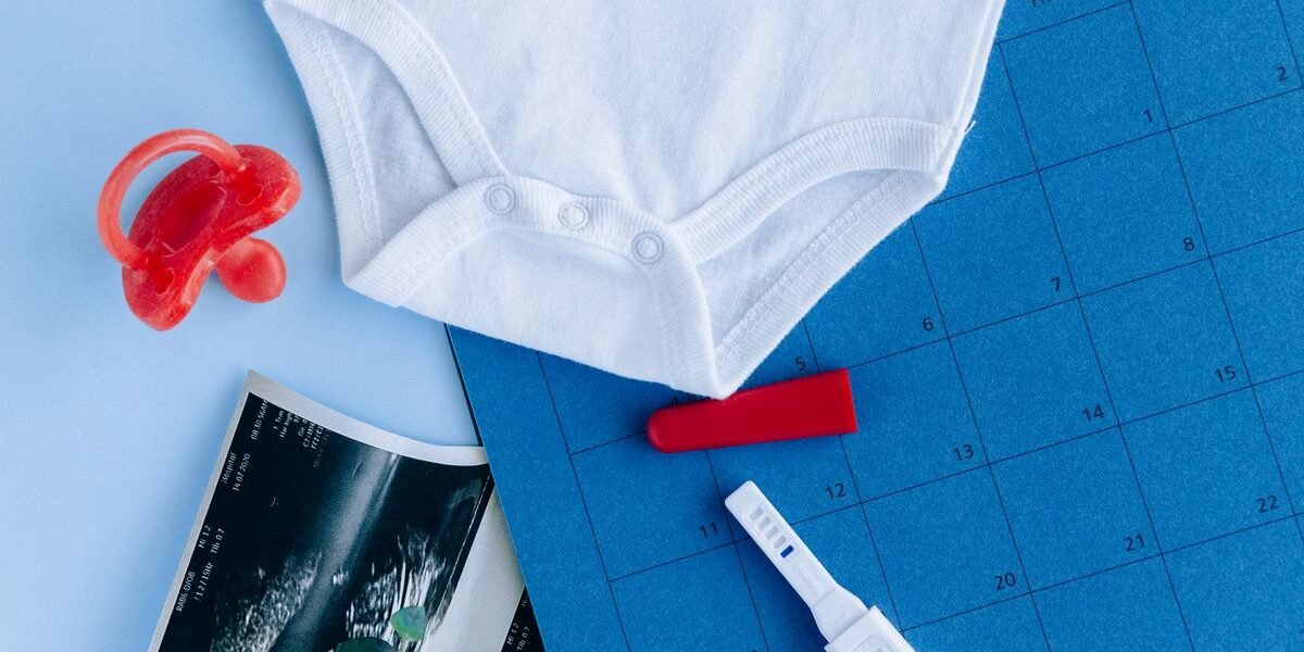 Complete geboortelijst op papier naast babykleertjes en een spuugdoek