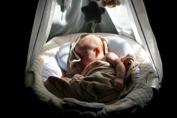 Pasgeboren baby slaapt in een wiegje tijdens de eerste nacht thuis
