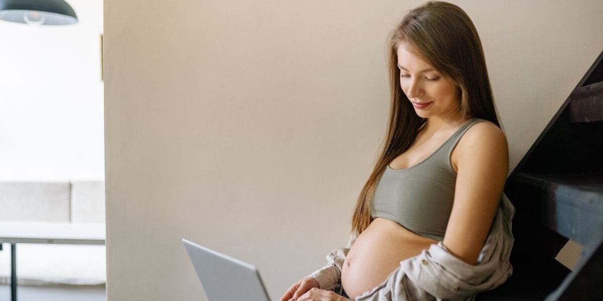Zwangere vrouw vinkt geboortelijst checklist af op laptop