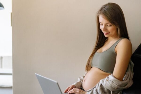 Zwangere vrouw vinkt geboortelijst checklist af op laptop