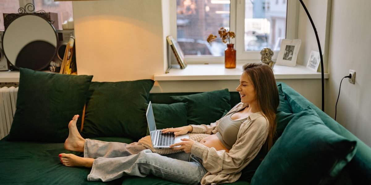 Zwangere vrouw bekijkt haar online geboortelijst op een laptop thuis