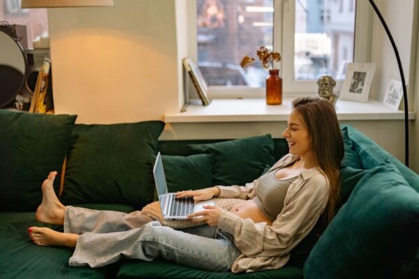 Zwangere vrouw bekijkt haar online geboortelijst op een laptop thuis