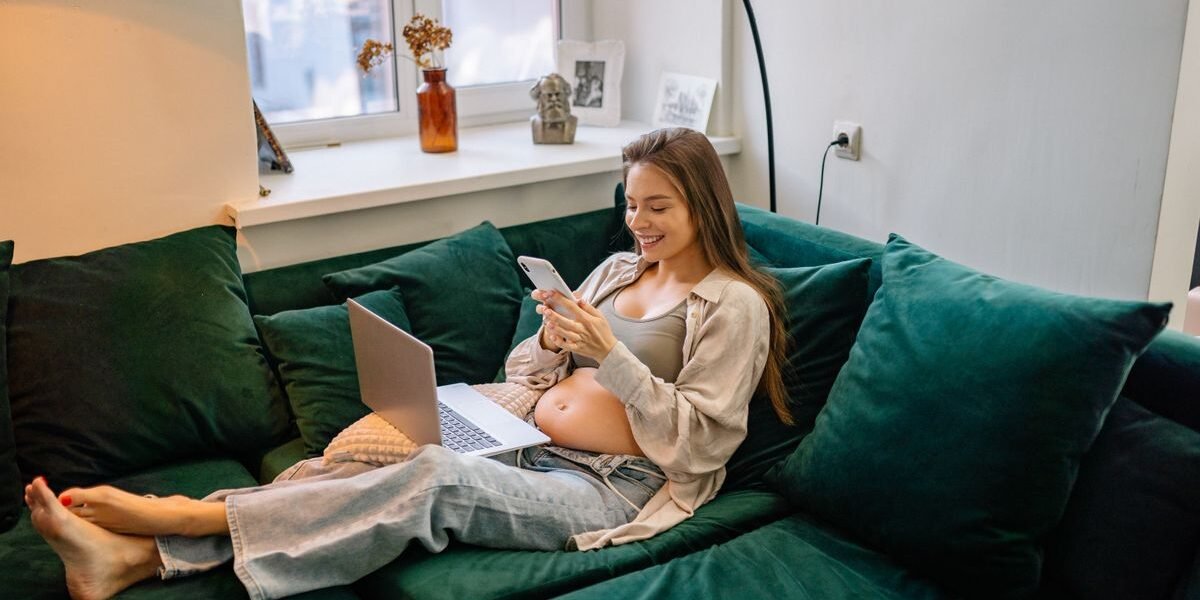 Zwangere vrouw plant haar geboortelijst met kalender en laptop