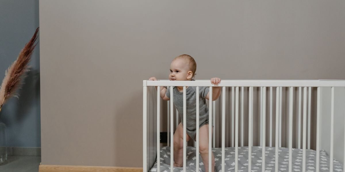 Eenvoudig wit ledikant in een rustige babykamer